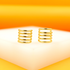 A pair of gold-plated multi-band ear cuffs rests on a white display against a warm orange background.