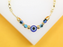 A delicate gold chain necklace features a central blue evil eye bead flanked by smaller glass evil eye beads and golden spheres.