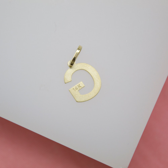 A polished 14K yellow gold initial G pendant rests against a white background.