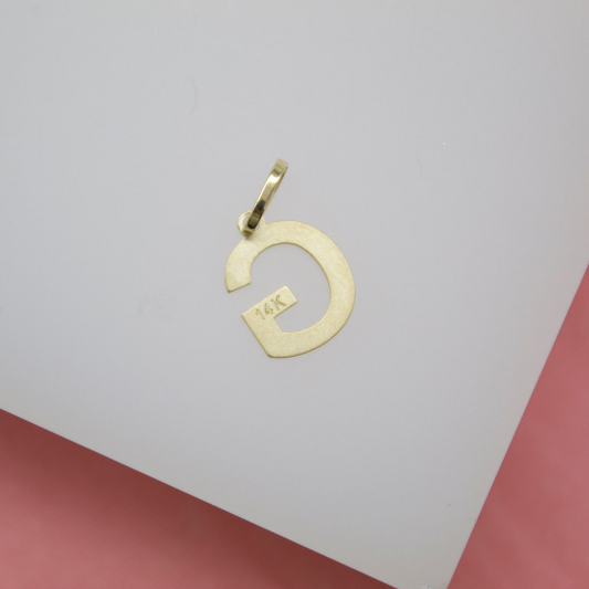 A polished 14K yellow gold initial G pendant rests against a white background.