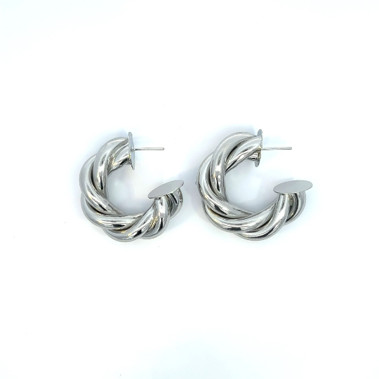 A pair of chunky silver twisted hoop earrings rests against a clean white background.
