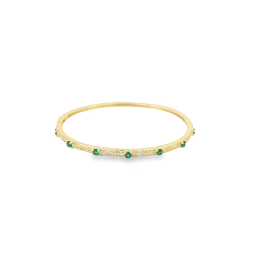 A sleek gold bangle bracelet sparkles with pavé diamonds and features evenly spaced round emerald stones.