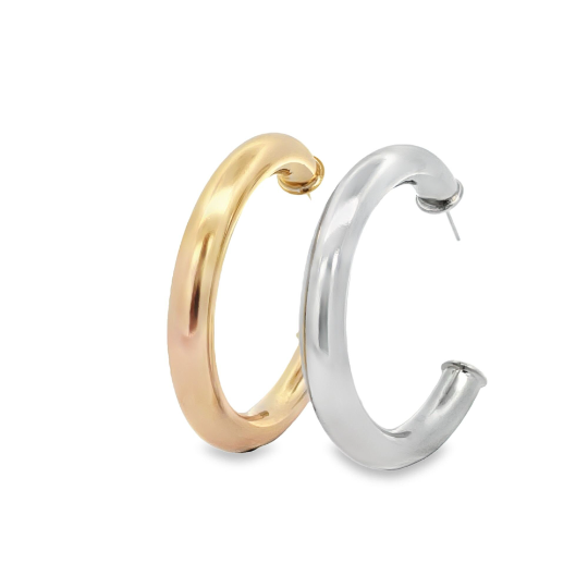 A pair of thick, polished gold and silver hoop earrings rests against a clean white background.