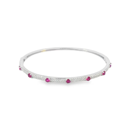 A silver diamond and ruby bangle bracelet sparkles against a clean white background.