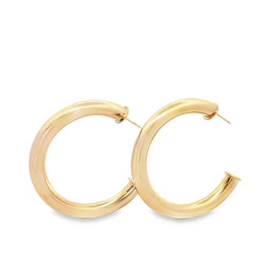 A pair of thick, polished gold hoop earrings rests against a clean white background.