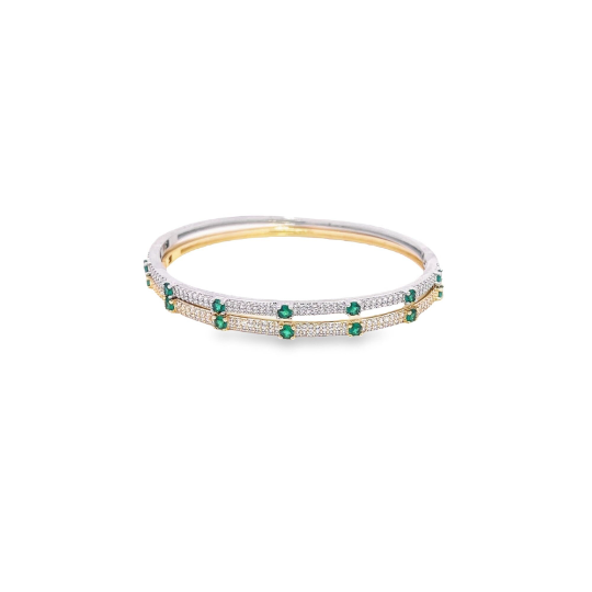 Two interlocking gold and silver bangles feature pavé-set diamonds and alternating vibrant green emerald stones against a clean white background.