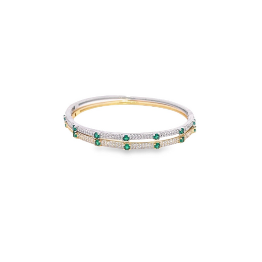 Two interlocking gold and silver bangles feature pavé-set diamonds and alternating vibrant green emerald stones against a clean white background.