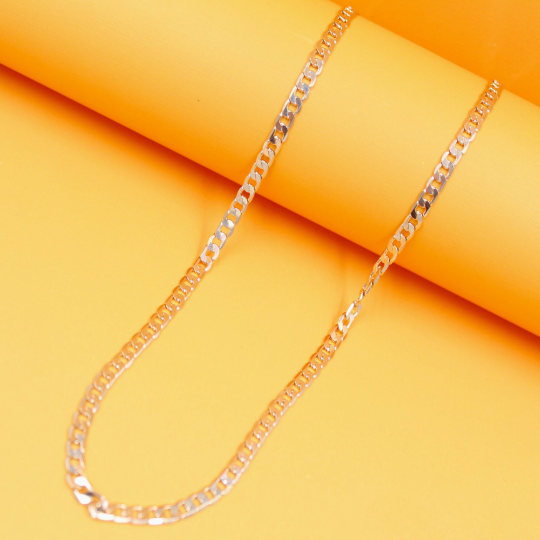 A gleaming gold-plated curb chain necklace rests gracefully against a vibrant yellow background.
