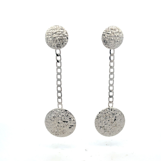 A pair of silver statement earrings features textured circular studs connected by delicate chain links to larger, hammered circular drops against a clean white background.