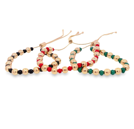 Three adjustable beaded bracelets featuring shiny gold spheres interspersed with black, red, and green accent beads rest against a white background.