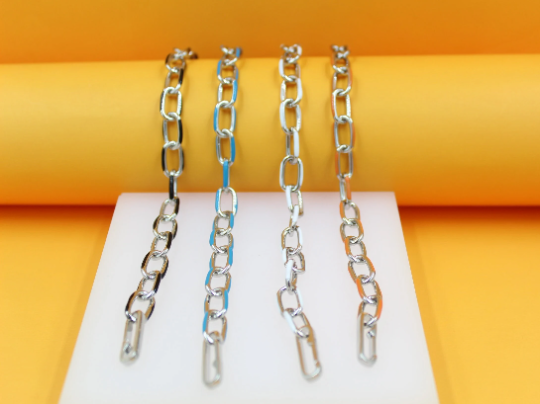 Four stylish metal chain necklaces in black, blue, white, and orange hang vertically against a vibrant yellow and white display.