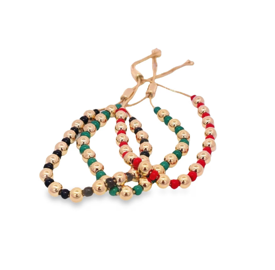 Three adjustable gold bead bracelets featuring red, green, and black accents rest on a white background.