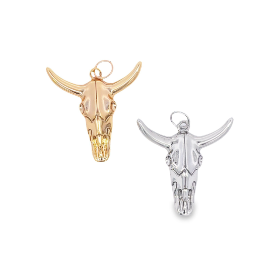 Two polished bull skull pendants, one gold and one silver, feature intricate detailing and attached jump rings against a clean white background.
