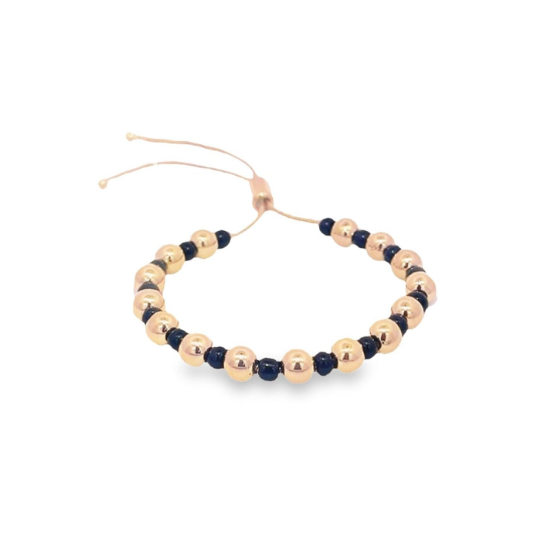 An adjustable rose gold beaded bracelet featuring alternating metallic spheres and dark blue beads rests against a white background.