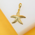 A detailed gold starfish pendant rests on a bright yellow and white surface.