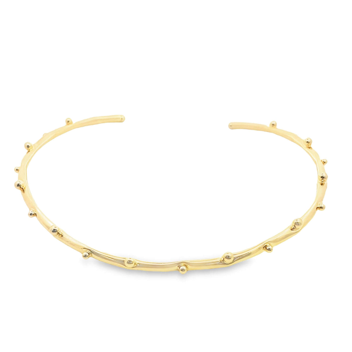 A sleek gold cuff bracelet features delicate, evenly spaced sphere accents along its open band against a clean white background.