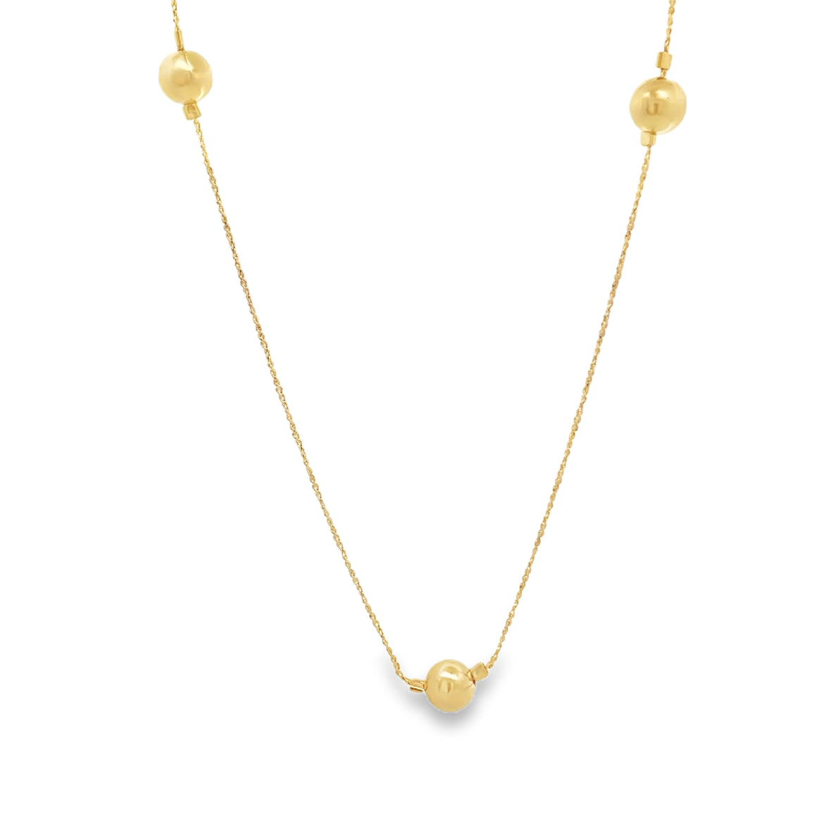 A delicate gold station necklace displays three polished gold beads spaced along a fine chain against a white background.