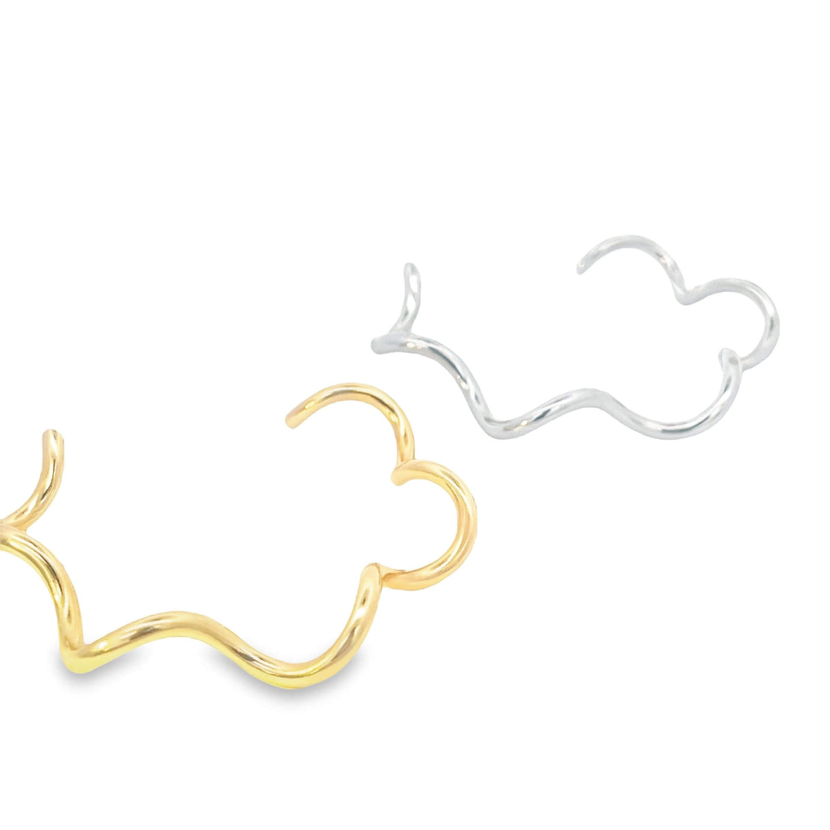 Two wavy metal cuffs, one in gold and one in silver, rest against a white background.