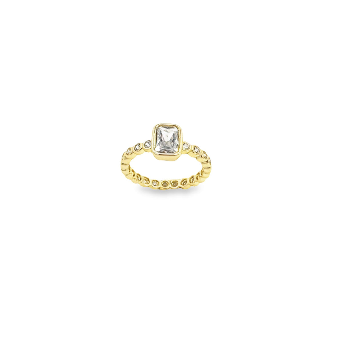 A gold ring features a central emerald-cut diamond flanked by smaller round stones along a textured band.