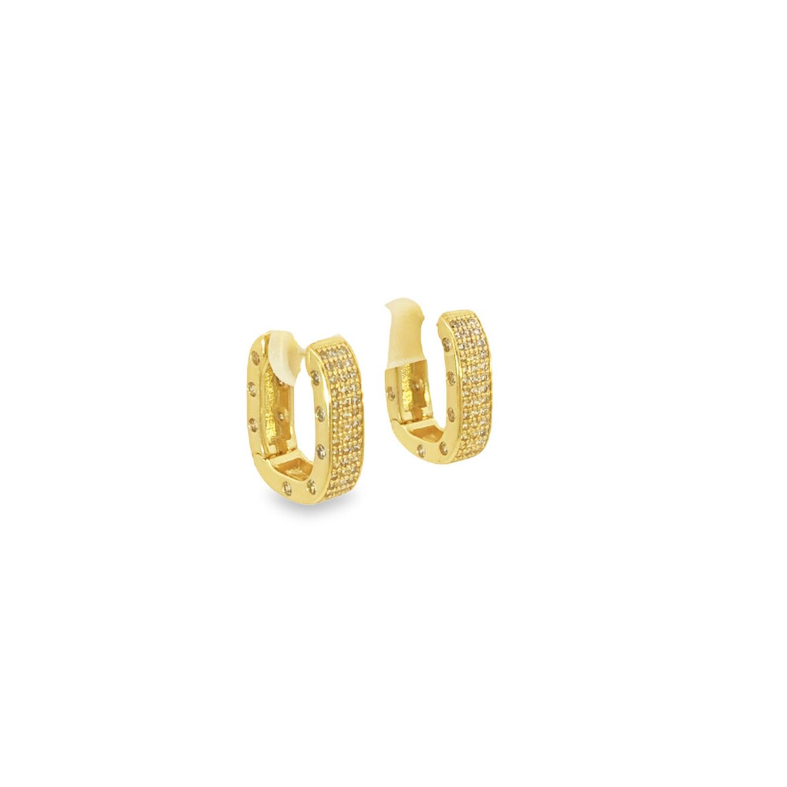 A pair of gold pave-set diamond huggie hoop earrings sparkles against a clean white background.