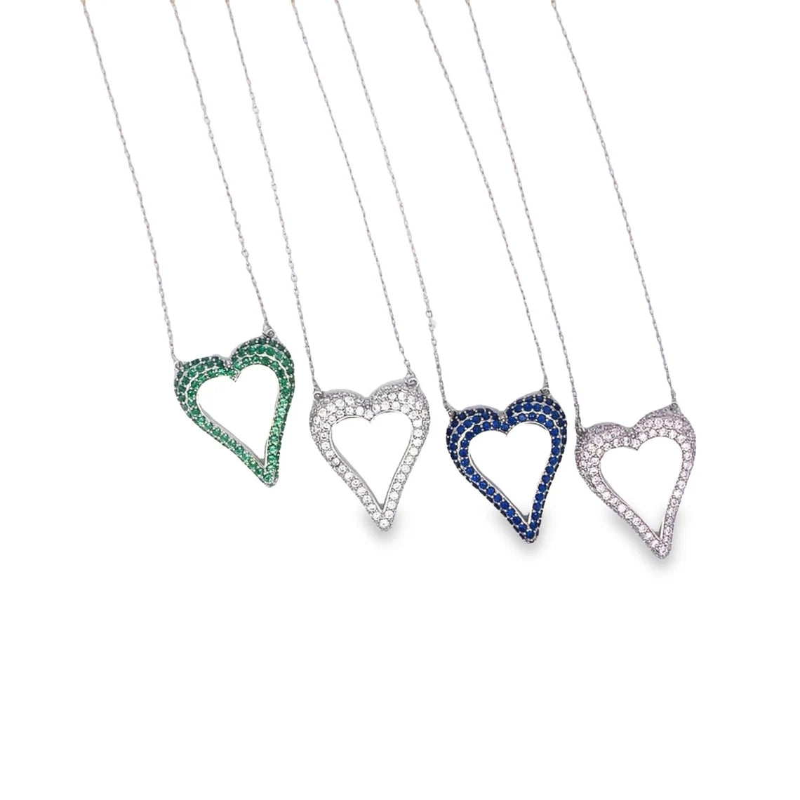Four delicate silver heart necklaces adorned with colorful cubic zirconia stones in green, white, blue, and pink sparkle against a white background.