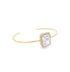 A delicate gold cuff bracelet features a large emerald-cut diamond accented by a sparkling pavé halo.