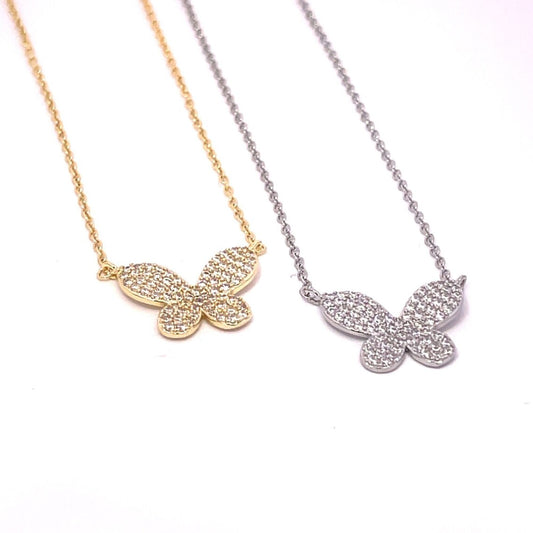 Two delicate butterfly pendant necklaces, one gold and one silver, feature sparkling cubic zirconia pavé stones against a clean white background.