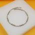 A silver spiral bangle bracelet featuring alternating polished metal beads and cubic zirconia stones rests on a white display surface.