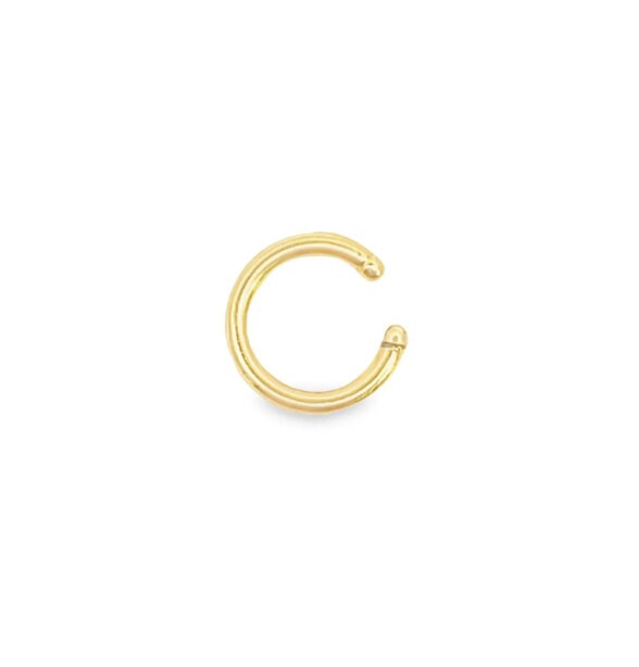 A polished gold nose ring hovers against a clean white background.