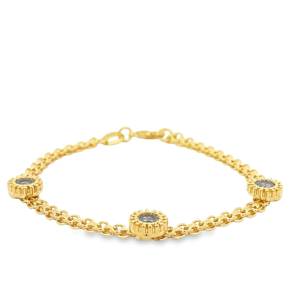 A delicate gold chain bracelet features three round station charms set with dark stones against a clean white background.
