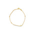 A delicate gold bracelet featuring spaced beads and an adjustable chain lies on a white background.