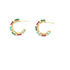 A pair of gold hoop earrings embellished with alternating red and green baguette stones rests against a plain white background.