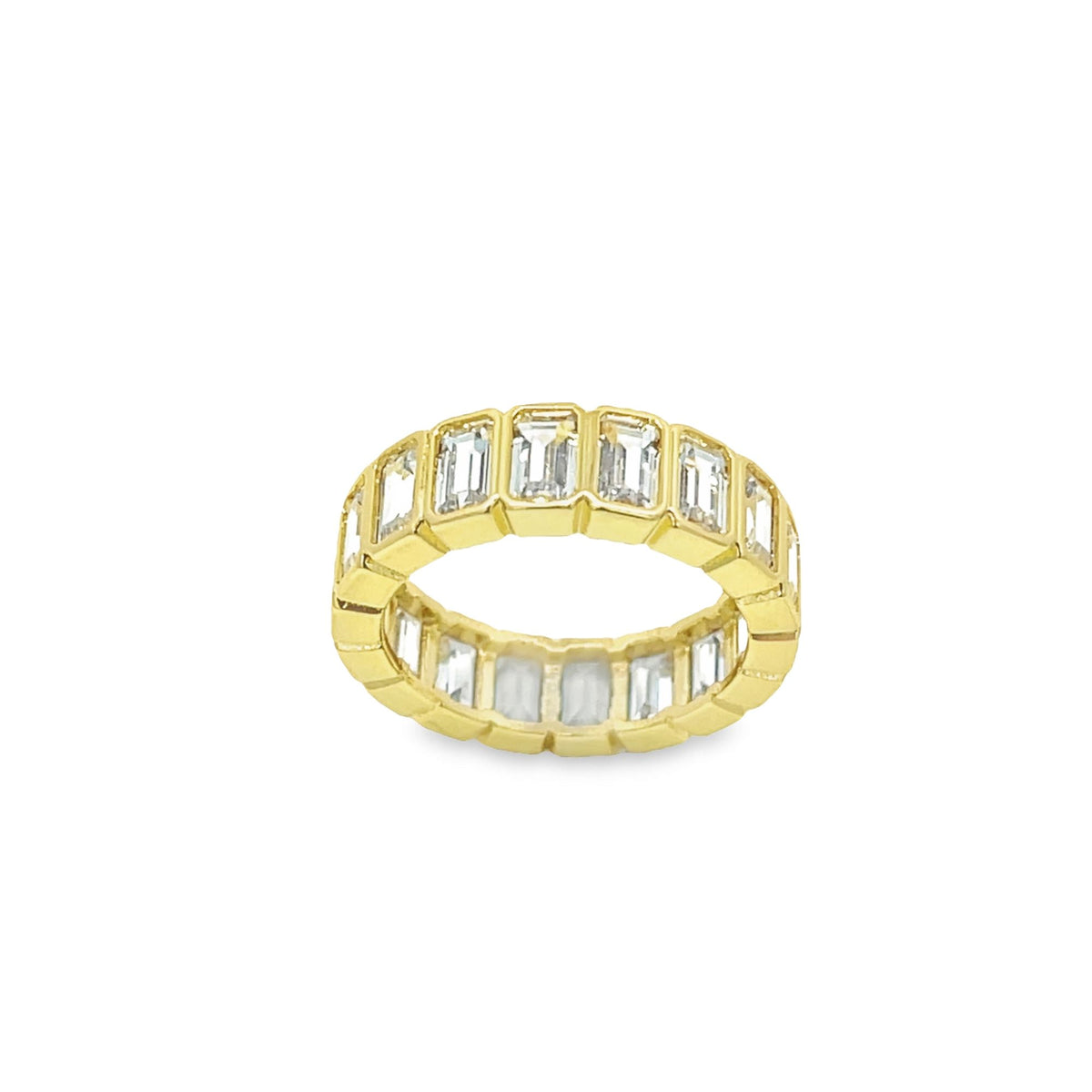 A gold eternity band features a continuous row of emerald-cut diamonds set against a white background.