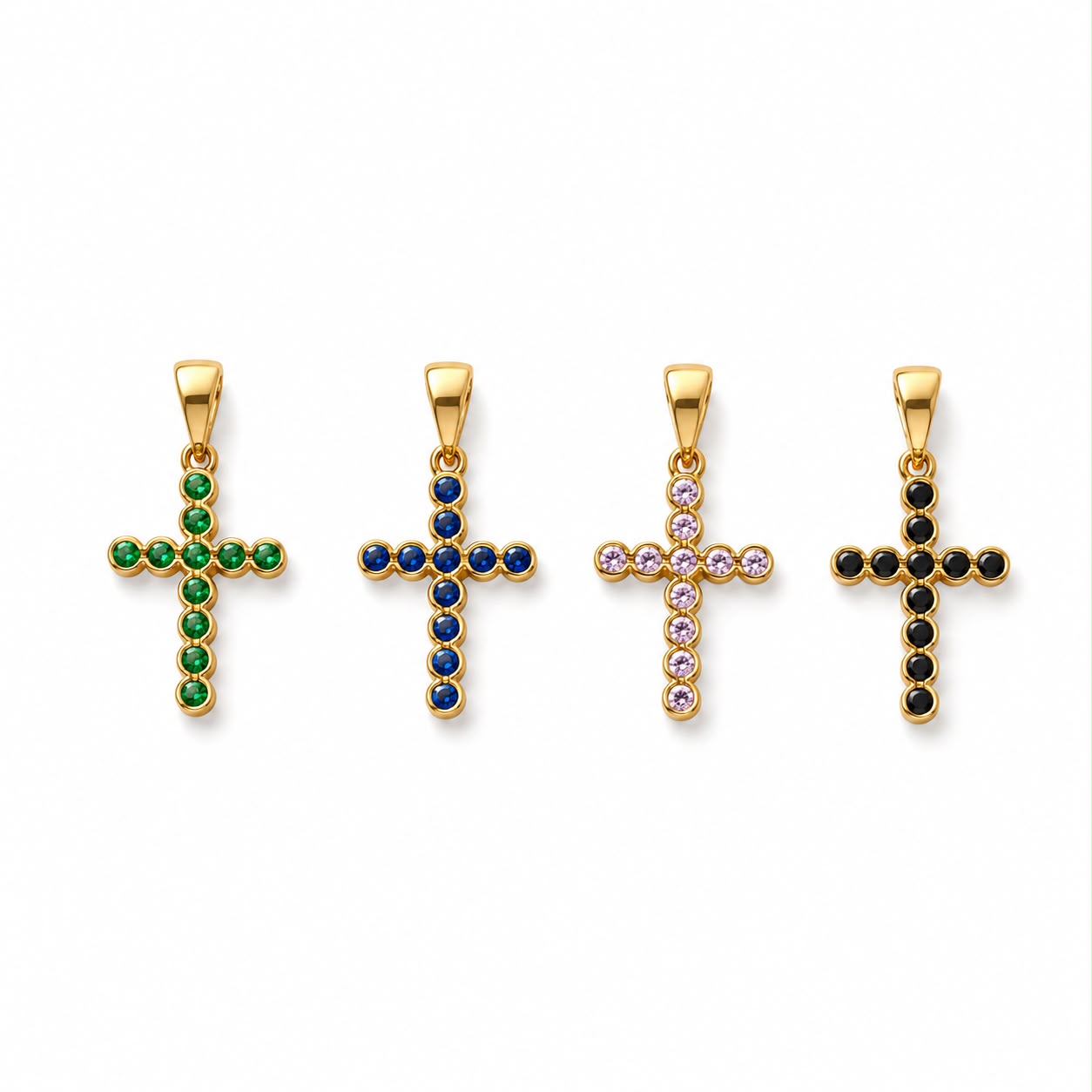 Four gold cross pendants adorned with green, blue, pink, and black gemstones are displayed against a clean white background.