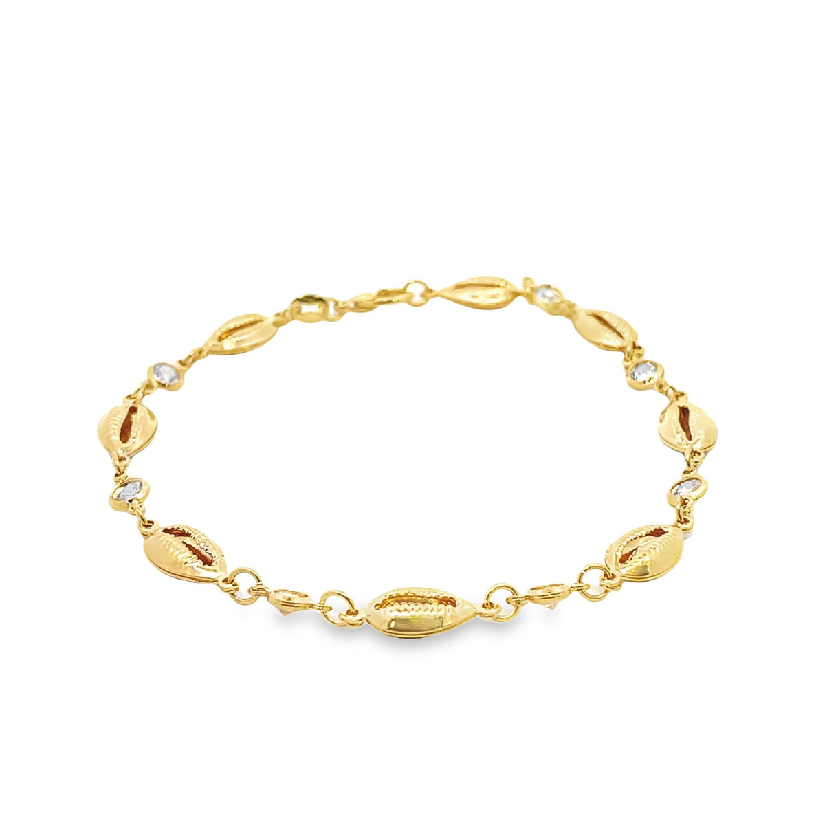 A delicate gold shell bracelet rests against a plain white background, featuring alternating cowrie shell charms and sparkling cubic zirconia stones.