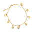 A gold charm anklet features dangling apple pendants interspersed with small red beads against a plain white background.