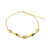 A gold chain anklet features three cowrie shell charms interspersed with colorful yellow, green, and orange beads against a white background.