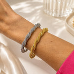 Elegant 18K Gold Filled twisted mesh cuff bracelet featuring a woven textured design with polished twisted accents. Lightweight, adjustable and perfect for everyday wear.