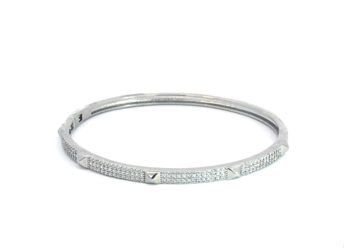 A silver diamond-pave bangle bracelet with studded pyramid accents rests on a clean white surface.