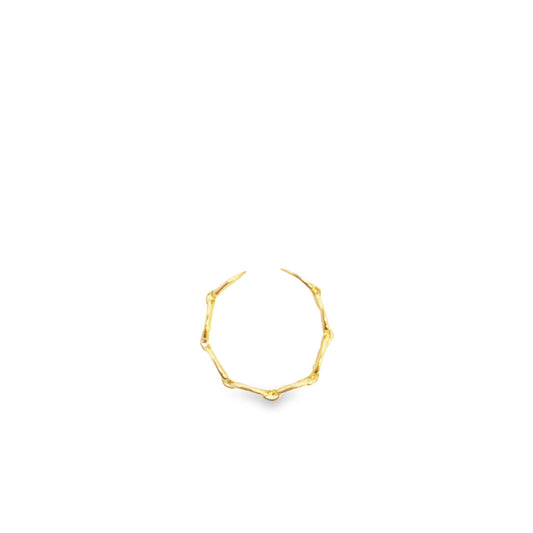 A delicate gold ring featuring a textured, organic branch design rests against a clean white background.