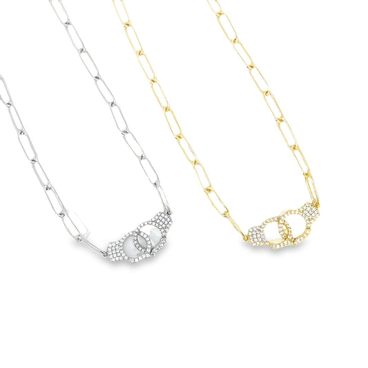 Two paperclip chain necklaces display interlocking handcuff pendants embellished with sparkling pavé diamonds in silver and gold tones.