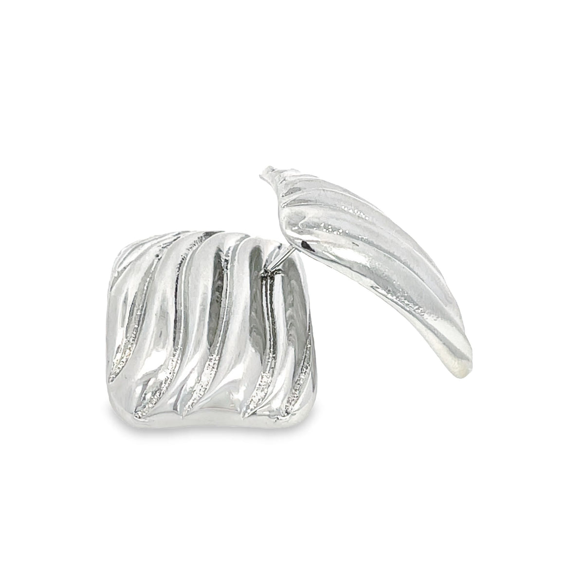 A pair of chunky silver croissant dome earrings sits on a clean white background, showcasing their unique fluted design.