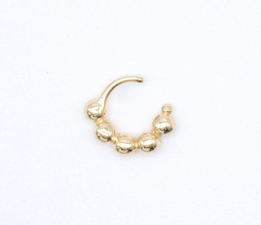 A gold beaded hoop piercing rests against a plain white background.