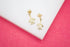 A pair of gold turtle stud earrings featuring sparkling crystal shells rests on a white display surface.