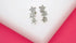 A pair of silver star climber earrings sparkle with cubic zirconia stones on a white display block.