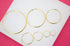 A collection of various sizes of minimalist gold hoop earrings arranged on a white display surface.