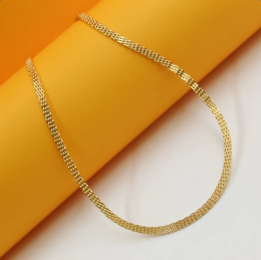 A delicate gold mesh chain necklace rests gracefully against a vibrant yellow and white background.