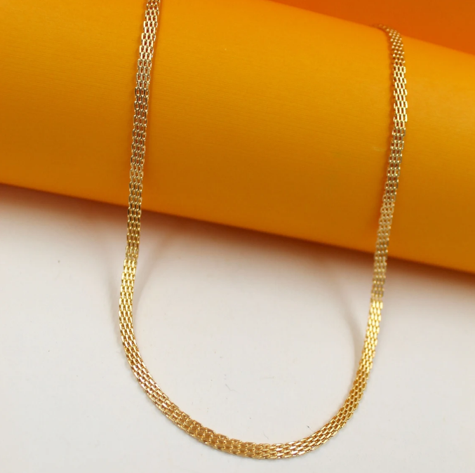 A delicate gold mesh chain necklace drapes gracefully against a vibrant orange and white background.