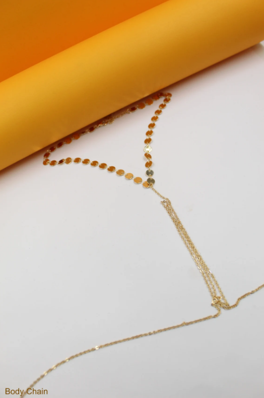 A delicate gold body chain rests on a white and yellow background.