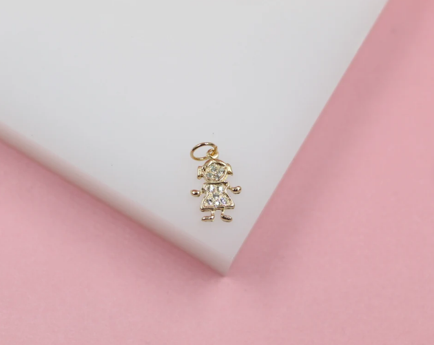 A gold little girl pendant rests on a white display against a pink background.